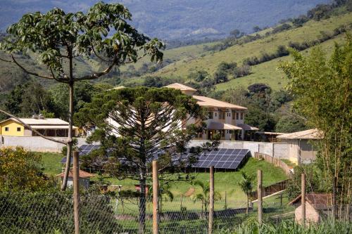 a house with solar panels on a green field at Hotel Águas Lindas in Itamonte