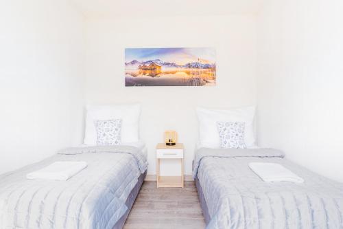 Un dormitorio con 2 camas y una mesa con una foto. en "AGUŚ" Komfortowe i nowczesne domki w cichej okolicy niedaleko plaży, en Ostrowo