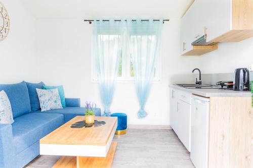 a living room with a blue couch and a table at "AGUŚ" Komfortowe i nowczesne domki w cichej okolicy niedaleko plaży in Ostrowo