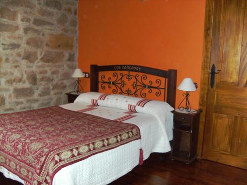 um quarto com uma cama grande e uma parede laranja em Los Cascayos em Abantro