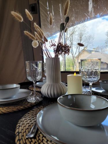 a table with plates and glasses and a vase with flowers at Glampinglodge 2 pers met hottub in Meerssen