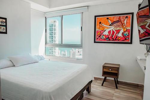 a white bedroom with a bed and a window at Playa Cartagena Apartments in Cartagena de Indias