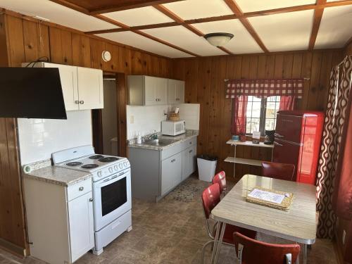 a kitchen with white appliances and a table with chairs at Lakeshore Fishing Cabin 5, dock, boat slip and firepit area in Lake Ozark