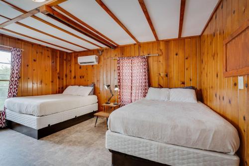 two beds in a room with wooden walls at Lakeshore Fishing Cabin 5, dock, boat slip and firepit area in Lake Ozark