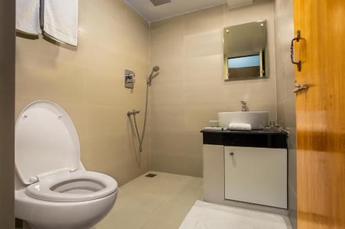 a bathroom with a white toilet and a sink at Memento Suites an Airport Hotel in Dhaka