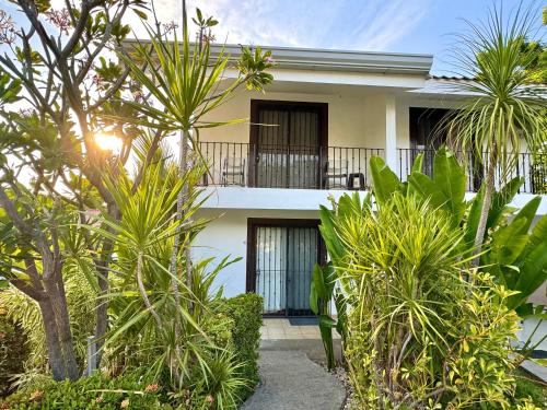 a white house with palm trees in front of it at Pura Armonia Condo With Outdoor Patio in Coco