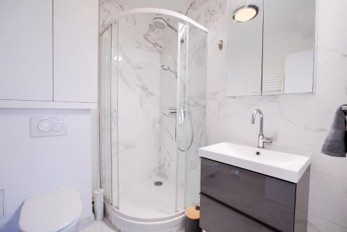 une salle de bain blanche avec une douche et un lavabo dans l'établissement Élégance Parisienne au cœur du Marais, à Paris