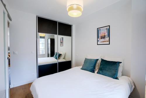 une chambre avec un lit blanc et un miroir dans l'établissement Élégance Parisienne au cœur du Marais, à Paris
