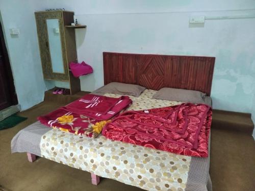 a bedroom with a bed with red blankets and a mirror at Shephard cheminèe in Pālampur