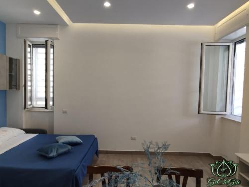 una camera da letto con un letto con lenzuola blu e due finestre di Al GeChiGiù a Bacoli