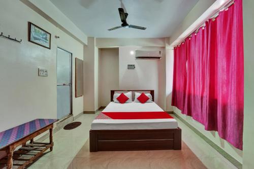 OYO Flagship Hotel CDS Regency في باتنا: غرفة نوم بسرير وستارة حمراء