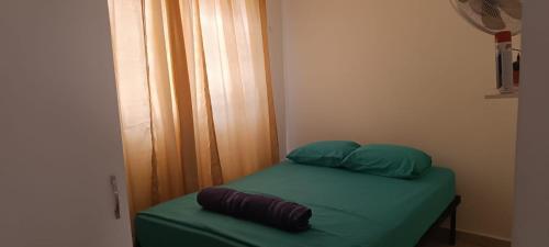 1 cama pequeña con sábanas y almohadas verdes en una habitación en Elegante Habitación 2 en Arraiján