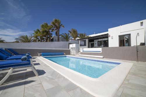 una piscina con sillas azules y una casa en Exquisite Lanzarote Villa | Villa Nova Vista | 4 Bedrooms | Spectacular Sea Views & Private Pool | Playa Blanca, en Playa Blanca