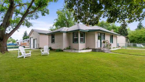 a house with two white chairs in a yard at Stylish & Bright 4BR - Close To Whitworth in Nine Mile Falls