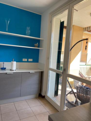 a kitchen with blue walls and a sliding glass door at Pool Apartment Bellagio in Bellagio