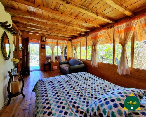 a bedroom with a bed and a couch and windows at Cabaña Mafer in Guatavita