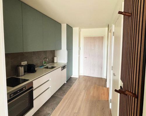 a kitchen with green cabinets and a wooden floor at Belgrade Waterfront-Beograd na vodi Galaxy Apartment in Belgrade