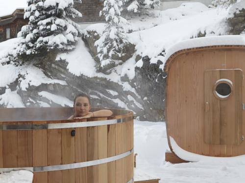 a woman in a hot tub in the snow at Hôtel des Dromonts by SOWELL COLLECTION in Avoriaz