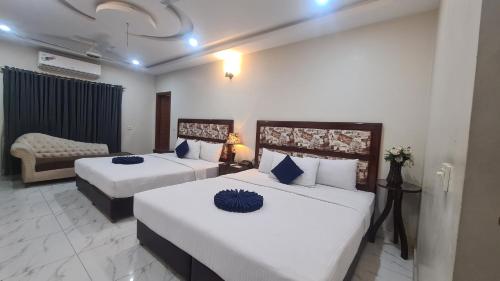 ein Hotelzimmer mit 2 Betten und einem Sofa in der Unterkunft Hotel Executive Lodges in Bahawalpur