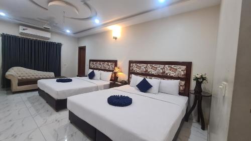 a hotel room with two beds and a couch at Hotel Executive Lodges in Bahawalpur