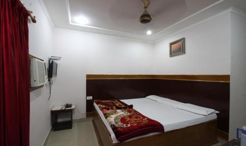 a bedroom with a bed with a red blanket on it at Hotel Ajay International in Agra
