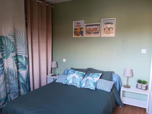 ein Schlafzimmer mit einem blauen Bett mit drei Bildern an der Wand in der Unterkunft Studio 37 m2 in Saint-Génis