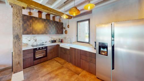 a kitchen with wooden cabinets and a stainless steel refrigerator at Château de Saint-Clair in Bordeaux-Saint-Clair