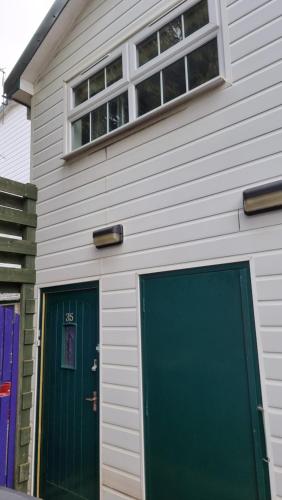 uma casa com uma porta verde e duas janelas em Little Harbour Self Catering em Stanley