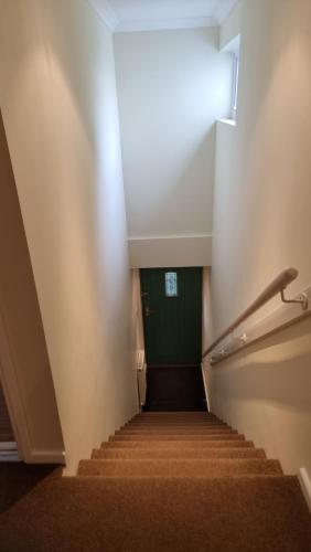 a stairway with a green door and a stair case at Little Harbour Self Catering in Stanley