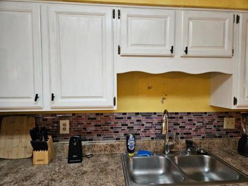 a kitchen counter with white cabinets and a sink at Peaceful & Elegant Sleeps 16 with Pool Near Mall in Memphis