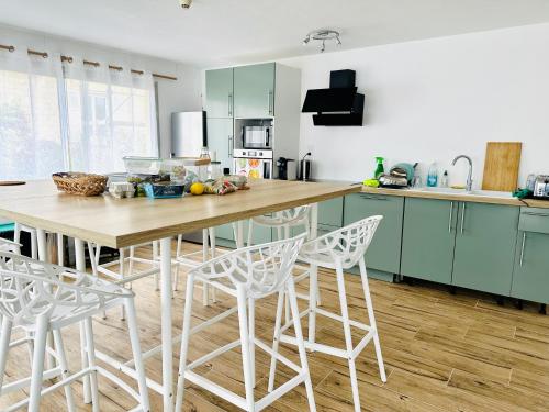 - une cuisine avec une table en bois et des chaises blanches dans l'établissement Le Cabieu, à Ouistreham