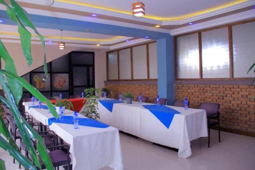 a room with white tables and chairs and windows at Ekshesh Hotel Bishoftu in Debre Zeyit