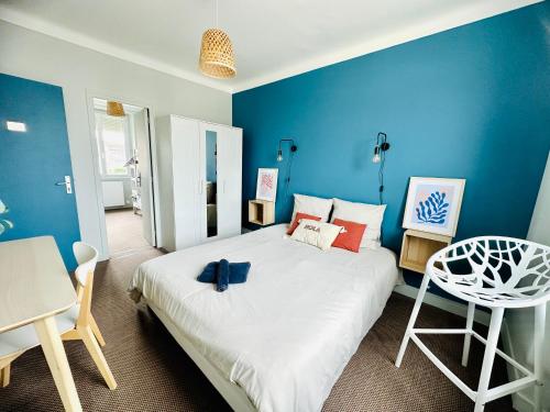 a bedroom with a large bed with blue walls at Le Cabieu in Ouistreham