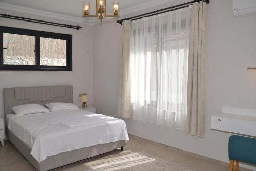 a white bedroom with a bed and a window at HYVillaS HÜMA in Muğla