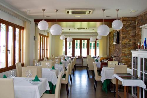 jadalnia z białymi stołami i krzesłami oraz oknami w obiekcie Hotel Mi Casa w mieście Antas