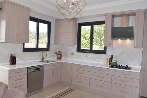 a kitchen with white cabinets and a sink and windows at HYVillaS HÜMA in Muğla