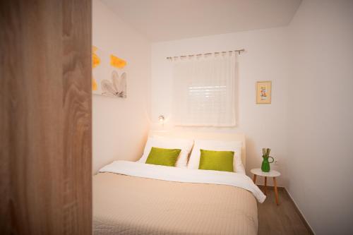 a bedroom with a white bed with green pillows at Villa Rajski Dvor in Bol