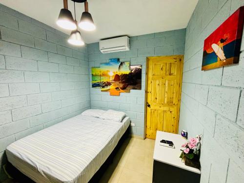 a bedroom with a bed and a white brick wall at Hostal Camila’s in Tamanique