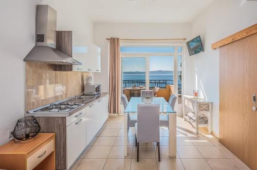 una cucina con tavolo e vista sull'oceano di Apartments Gudelj a Podgora