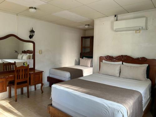 a hotel room with two beds and a desk and a desk at Hotel Javy in Liberia