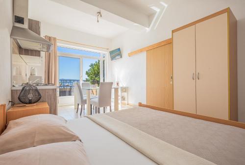 1 dormitorio con 1 cama y cocina con mesa en Apartments Gudelj, en Podgora