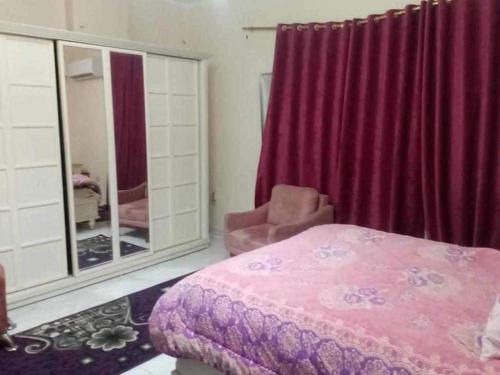 a bedroom with a pink bed and a chair and a mirror at غرفه فندقيه للإيجار ( فيلا الاسعد ) امام مول العرب in 6th Of October