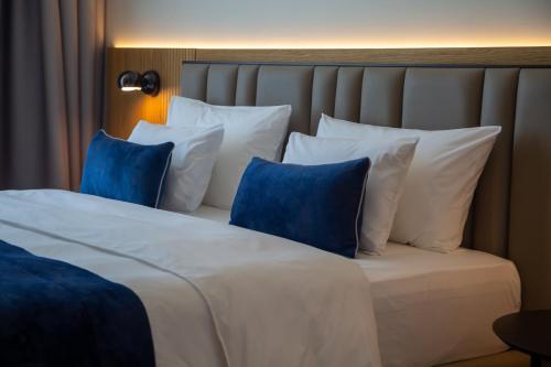 a bed with blue and white pillows in a room at Abi's Hotel & SPA Vlore in Vlorë