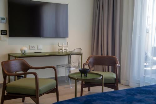 a room with two chairs and a table and a tv at Abi's Hotel & SPA Vlore in Vlorë