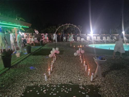 a group of people standing around a pool at night at Il Rustico in Pozzillo