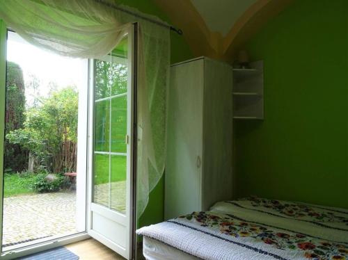 Agroturystyka Leszczynki في ليشنا: غرفة خضراء بسرير وباب زجاجي منزلق
