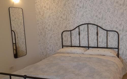 uma cama com duas almofadas num quarto com papel de parede em Villa Geltrude em Cusio