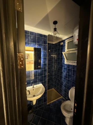 W wyłożonej niebieskimi kafelkami łazience znajduje się umywalka i toaleta. w obiekcie Porto El Sokhna Aqua park w mieście Ajn Suchna