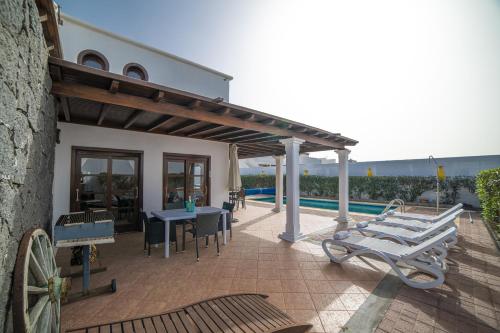 um pátio com uma mesa e cadeiras ao lado de um edifício em Sophisticated Lanzarote Villa | Villa Mervella | 4 Bedrooms | Spacious Terrace Area & Private Pool | Playa Blanca em Playa Blanca