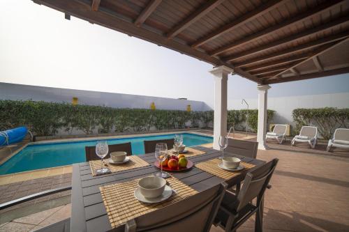 uma mesa e cadeiras sentadas ao lado de uma piscina em Sophisticated Lanzarote Villa | Villa Mervella | 4 Bedrooms | Spacious Terrace Area & Private Pool | Playa Blanca em Playa Blanca